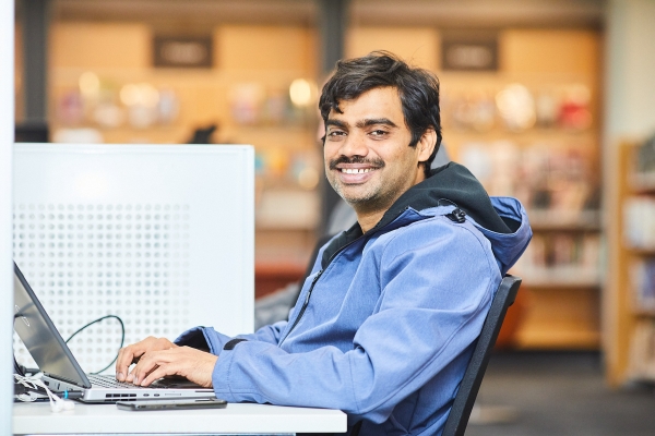 Library user at Connected Libraries using a laptop and smiling