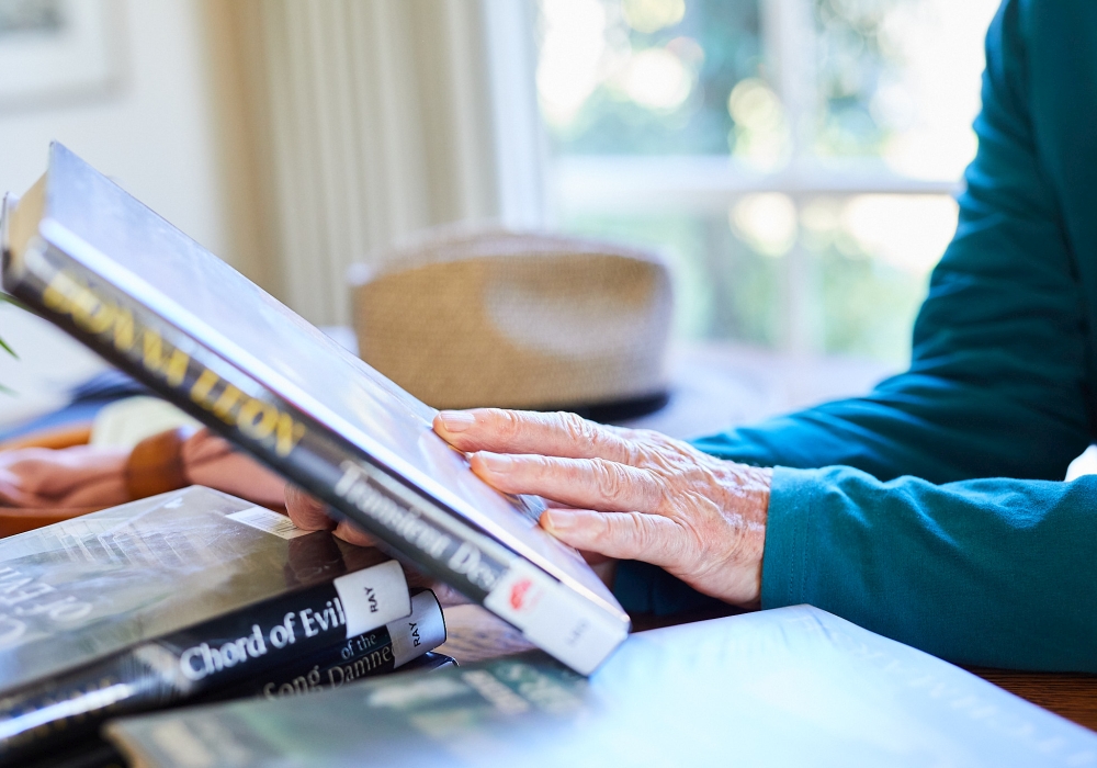 Elderly member at Connected Libraries with books from the home library service